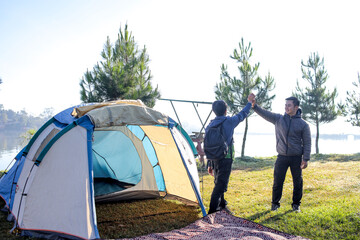 Two Happy Asian Men Giving Each Other a High Five After Setting up Their Tent by a Scenic Lake