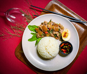 Stir-fried  pork leg with holy basil served over rice, a popular Thai street food dish full of spicy and aromatic flavors.