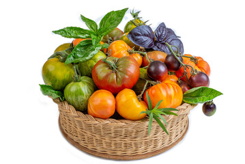 Colorful assortment of fresh tomatoes in a basket on white