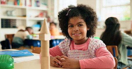 Building blocks, learning and portrait of student girl at desk in classroom of elementary school....