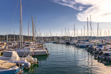 Fototapeta premium scenic marina with sailboats and yachts under clear blue sky at golden hour. colorful seascape with small marina in warm
