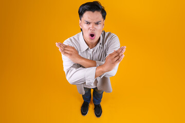 High Angle View Of Young Male Crossing Hands Gesture Rejection On Yellow Background