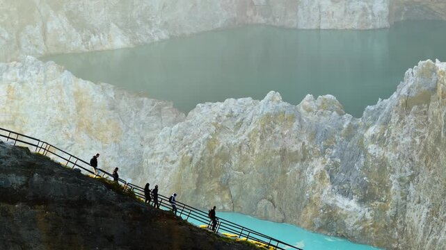 Aerial view of tourists on a wooden path enjoying the contrasting blues and whites of the Kelimutu crater lakes, Kelimutu, East Nusa Tenggara, Indonesia.