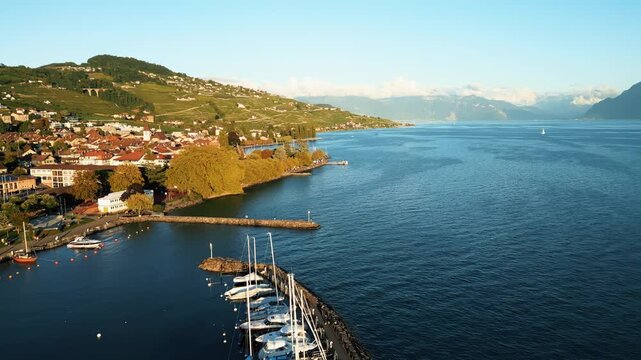 Aerial view of Lutry port, with boats docked along the pier and the village nestled against the backdrop of rolling hills, Lutry, Vaud, Switzerland.