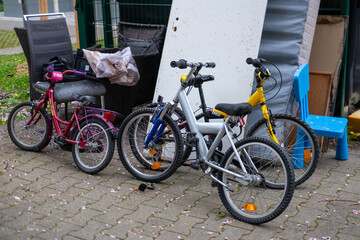Three colorful children's bicycles parked on a paved patio, surrounded by outdoor furniture and...