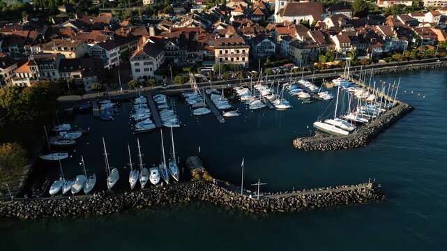 Aerial view of the boats docked in the harbour surrounded by quaint buildings, creating a beautiful contrast against the serene waters, Lutry, Vaud, Switzerland.