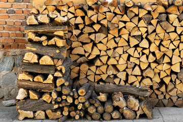 An extensive woodpile, consisting of split and whole logs, is meticulously stacked next to a rustic...