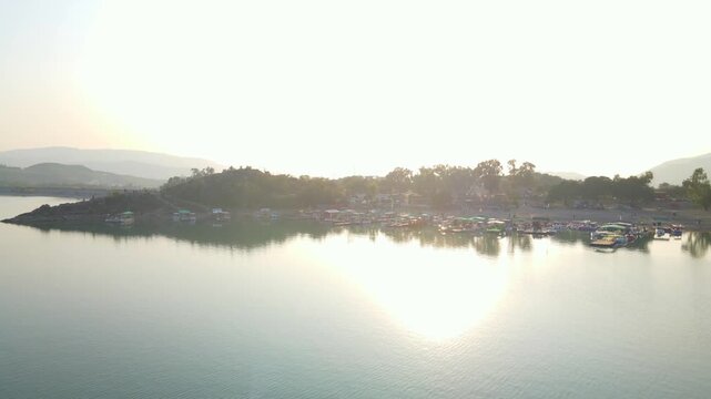 Aerial view of Khanpur Lake with boats docked along the shore, reflecting sunlight on the water, Khanpur, Khyber Pakhtunkhwa, Pakistan.