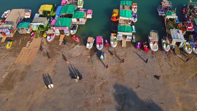Aerial view of boats with colorful roofs docked at Khanpur Lake, reflecting the clear sky in the turquoise water, Khanpur, Khyber Pakhtunkhwa, Pakistan.
