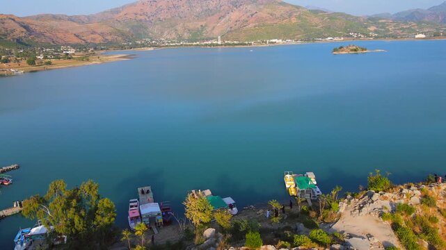 Aerial view of boats docked along the turquoise waters of Khanpur Lake with mountains in the background, Khanpur, Khyber Pakhtunkhwa, Pakistan.