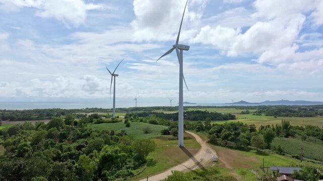 Aerial view of wind turbines with rotating blades set against the backdrop of the sea, Guimaras, San Lorenzo, Western Visayas, Philippines.