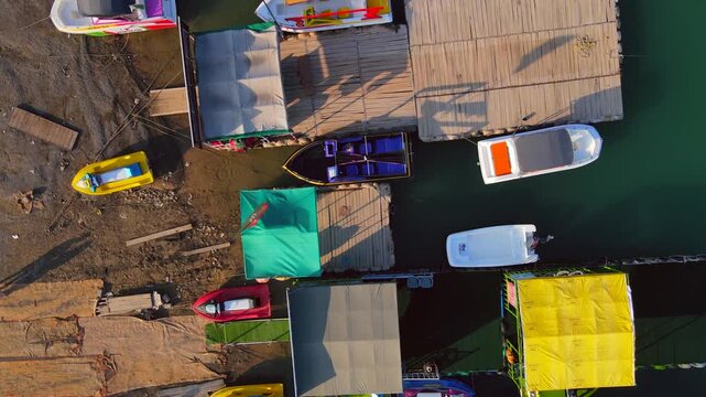 Aerial view of colorful boats docked on wooden piers along the tranquil waters of Khanpur Lake, Khanpur, Khyber Pakhtunkhwa, Pakistan.