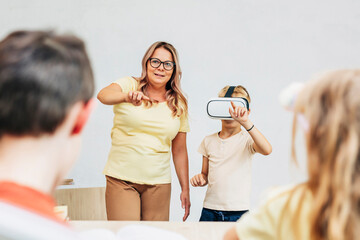 Teacher assisting student using virtual reality headset in classroom