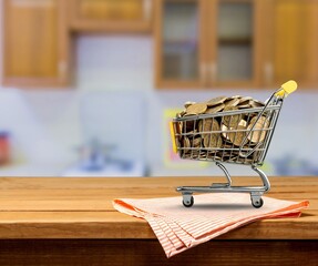 Money coins in a trolley shopping cart