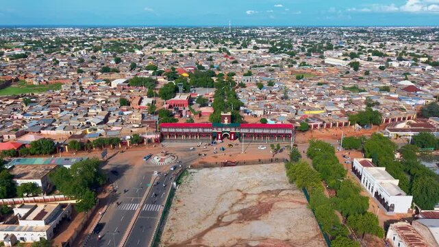 Katsina, Nigeria - 28 August 2025: Aerial view of the Emir Palace, a landmark with red roofs, surrounded by a bustling cityscape under a clear sky.