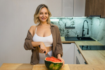 A sensual woman enjoys a slice of juicy watermelon in a modern kitchen. Confident, playful, and...