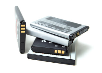 A pile of various old and used lithium-ion batteries from smartphones, isolated on a pure white...