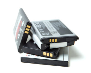 A pile of various old and used lithium-ion batteries from smartphones, isolated on a pure white...