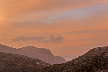 Olympos, Karpathos , Greece,  rolling hills and mountains beneath a vibrant orange sky. soft...