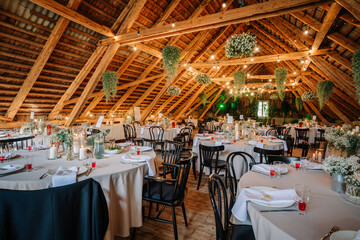 Charming rustic wedding reception setup in a wooden attic venue, decorated with string lights,...