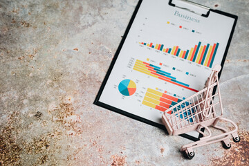 Business Analysis with Charts and Mini Shopping Cart on Textured Surface for Marketing and Economics Concepts