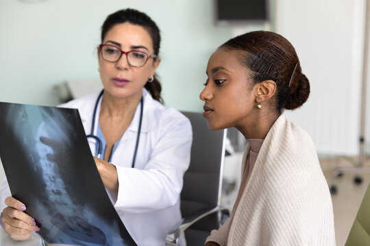 Elderly female explains spinal xray results to young female patient