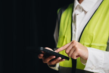 Safety Worker in High Visibility Vest Using Smartphone for Communication and Task Management in Industrial Setting