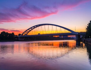 A beautiful arch bridge spans a tranquil river at sunrise, reflecting the vibrant colors of the sky in the calm water.
