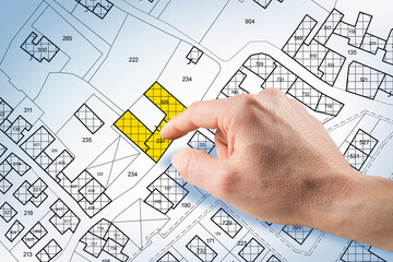 REAL ESTATE PROPERTY MAP WITH HAND SELECTING LAND PLOT ON CADASTRAL MAP - Concept of investment,...