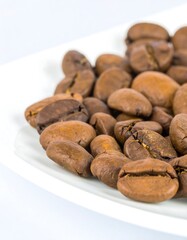 Obraz premium Roasted coffee beans on a white plate