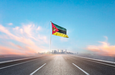 Mozambique national flag with mast waving with beautiful skyline. A view from highway. Mozambique...