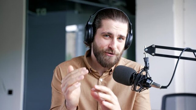 Webcam view Confident businessman in headphones recording podcast using microphone in business office. Tutor giving video call training looking at camera. Blogger is streaming. Coach has online course
