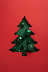 Creative vertical holiday card displaying a red background with a cut-out Christmas tree filled with ornaments