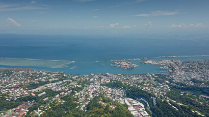 Breathtaking aerial view capturing Papeete vibrant cityscape along the pacific ocean, with a bustling harbor and a distant coral reef enhancing the tropical paradise