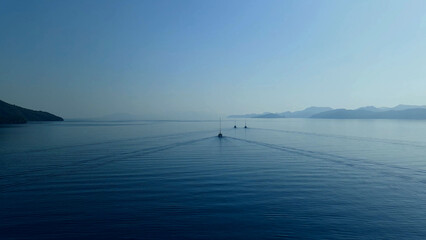Idyllic view of a wide sea channel between islands with three yachts on a calm surface of water  © AnyVIDStudio