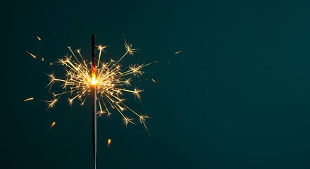 A single sparkler emitting bright sparks against a dark teal background