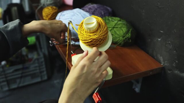 Close up of craftswoman using yarn ball winder 