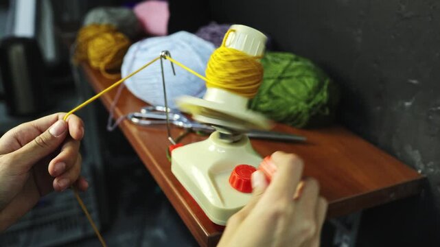Slow motion of craftswoman rolling threads on ball winder 