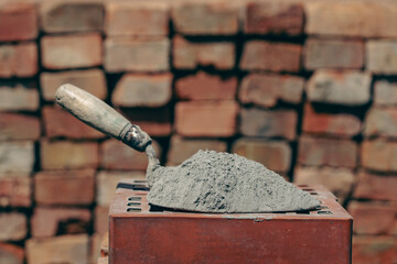 Dry cement or mortar. Cement powder and trowel on red brick at construction site, closeup