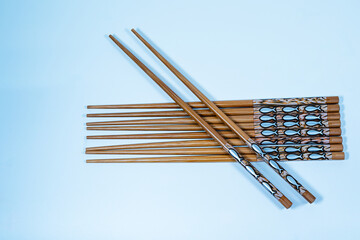 Set of traditional wooden chopsticks with decorative fish designs, arranged neatly on a light blue...