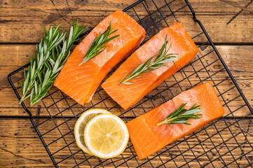 Salmon steaks, raw fish fillets on a rack with rpsemary. wooden background. top view
