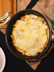 Double cheese pineapple pizza served in a hot pan, rich, cheesy, and delicious with a tropical twist.