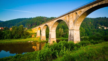 Fototapeta premium Stone arch bridge over river at dawn