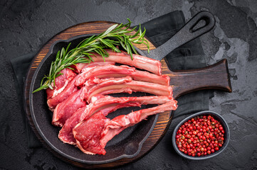 Ready for cooking Raw lamb meat chops, fresh mutton cutlets in a pan. black background. top view