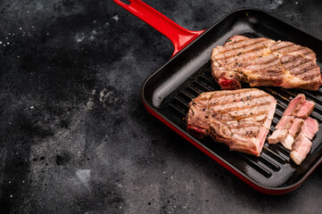 Fried on grill skillet pork tender steak, neck meat. black background. top view