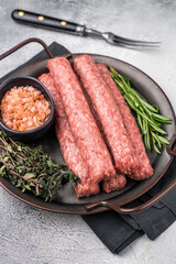 Raw Cevapcici ready for the grill, fresh Cevapi from mince beef meat. grey background. top view