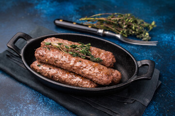 Grilled Cevapcici Sausage, roasted Cevapi from mince beef and pork meat in a skillet. blue background. top view
