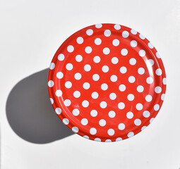 tin for canning closed with a red polka dot lid isolated on white background, top view