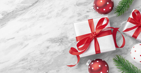 Christmas holiday background, white silver gift box with red bow ribbon and xmas ornaments decor on white marble table, top view