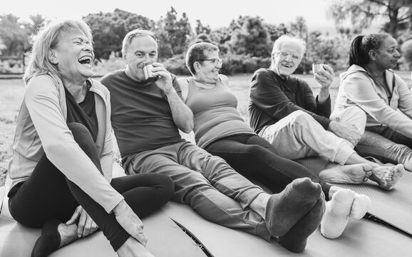 Senior people having fun drinking hot tea after yoga lesson at city park - Joyful elderly lifestyle and sport concept - Focus on left latin woman face - Black and white editing - Powered by Adobe